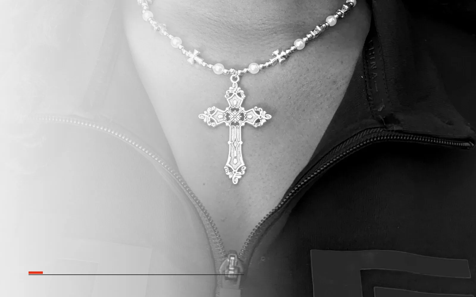 Silver gothic cross pendant on a beaded chain, worn at the collar